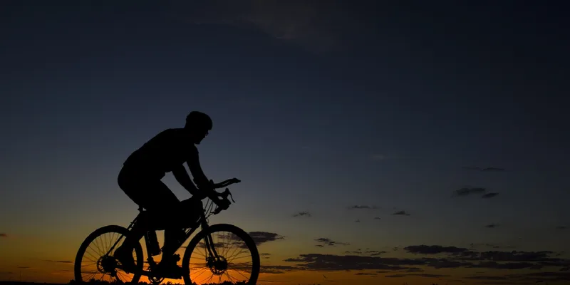 Siluett av cyklist mot dramatisk solnedgång