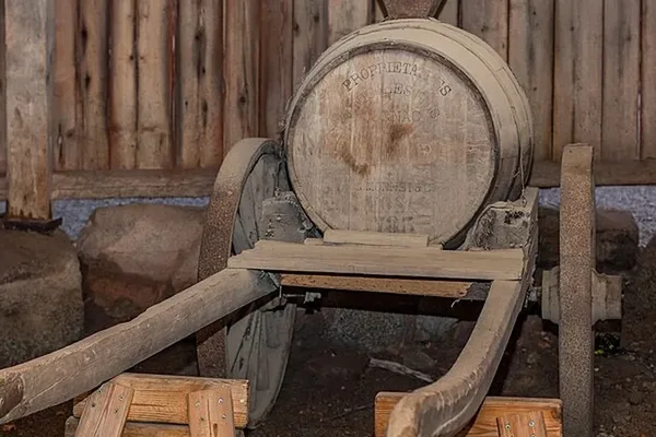 Gammal trätunna på kärra framför röd trävägg, brukshistoria