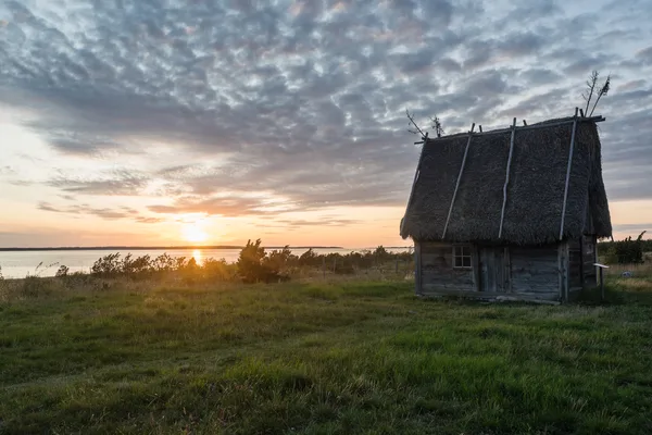 Gammalt fiskebodstak vid solnedgång över havet på Fårö