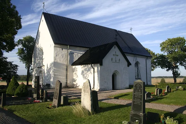 Österunda kyrka, en vitputsad medeltidskyrka omgiven av öppna uppländska åkrar