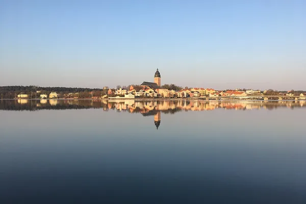 Strängnäs domkyrka speglar sig i Mälarens stilla vatten en tidig morgon