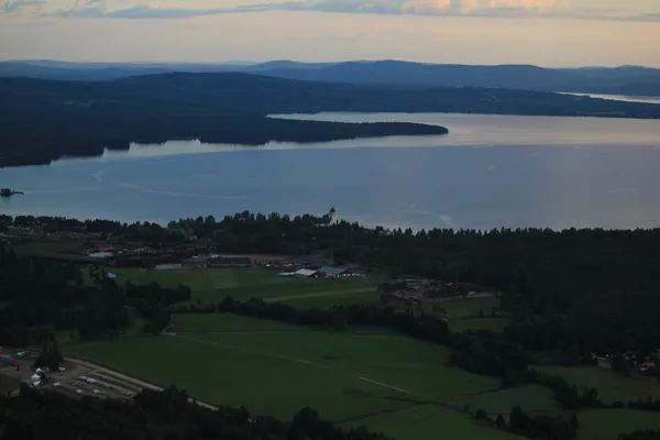 Kvällsvy över Siljan med samhälle, kyrka och skogsklädda höjder